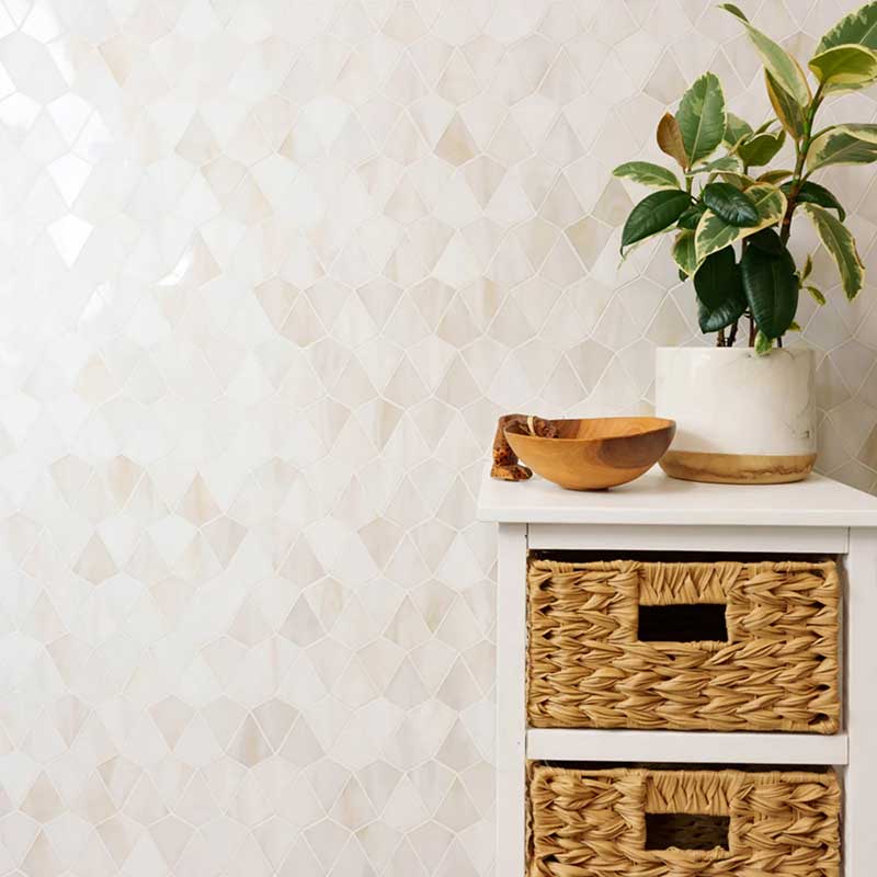 A white cabinet with woven baskets, a small plant in a white pot, and a wooden bowl set against a light geometric-patterned wall showcases the refined touch of a premium tile Florida design.